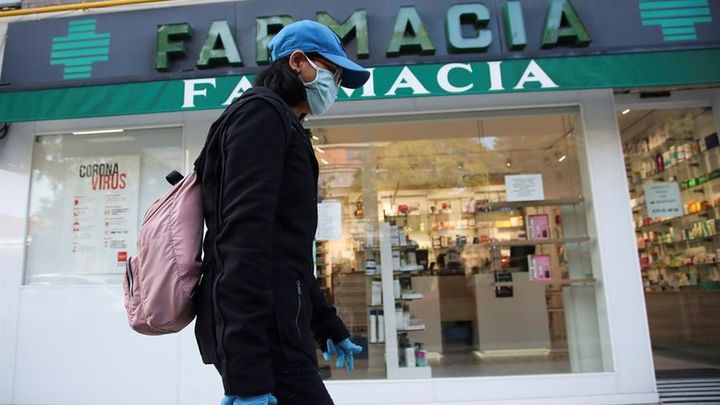 Una persona camina delante de una farmacia / EFE