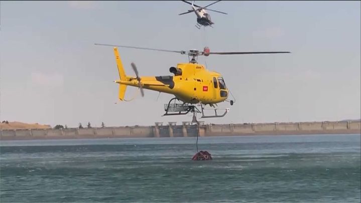 Uno de los helicópteros toma agua en el cercano embalse de Navacerrada / TELEMADRID