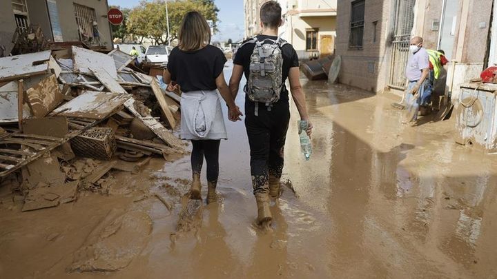 Una pareja camina por una calle de la localidad de Alfafar, en Valencia, este sábado, una de las zonas más afectadas por la dana que ha provocado ya 211 víctimas / EFE